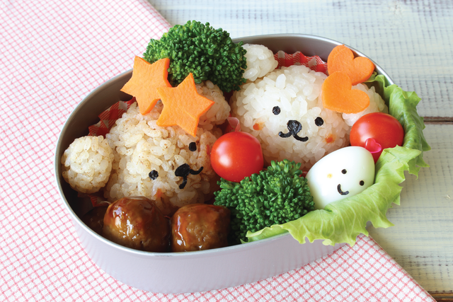 A bear-themed bento box lunch with little bears made out of rice, star and heart-shaped carrots, and a small egg with a smiley face. 