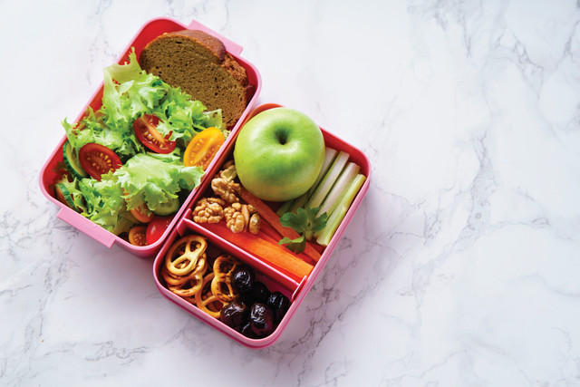 A pink bento box filled with healthy foods for a school lunch. 