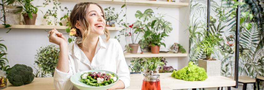 Woman eating a salad to keep her thyroid levels regulated with her synthetic hormone.