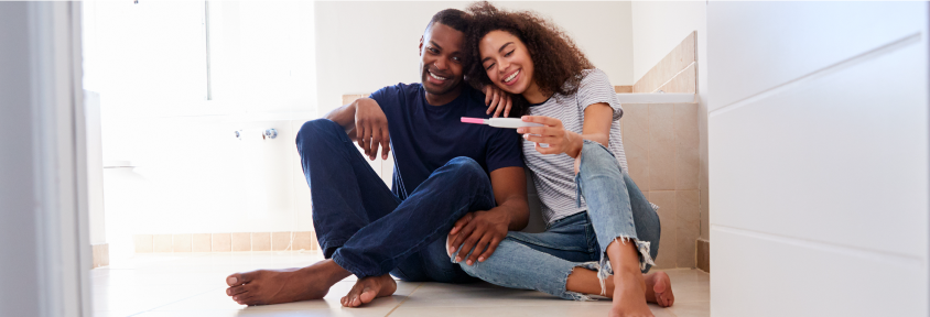 A couple smiles at a positive pregnancy test after overcoming infertility.