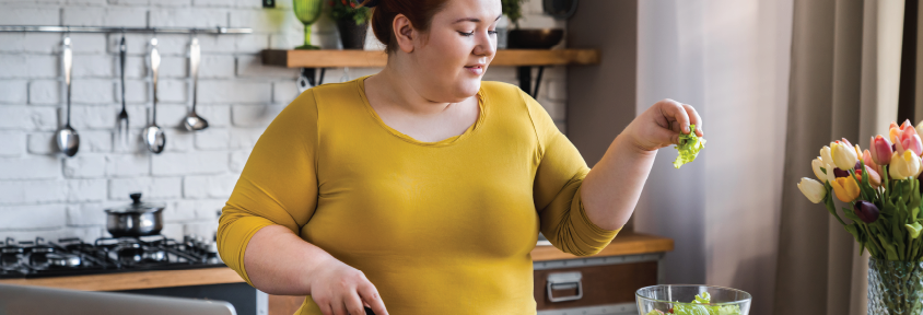 Plus-sized woman practicing mindful eating for weight loss by cooking at home.